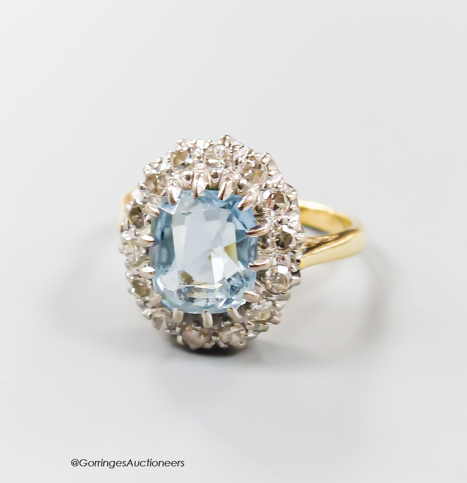 An 18ct, aquamarine and diamond set oval cluster ring, size N, gross 6 grams.